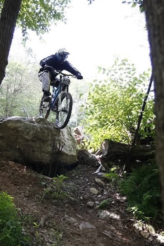 A rider on a mountain bike dropping off a rock