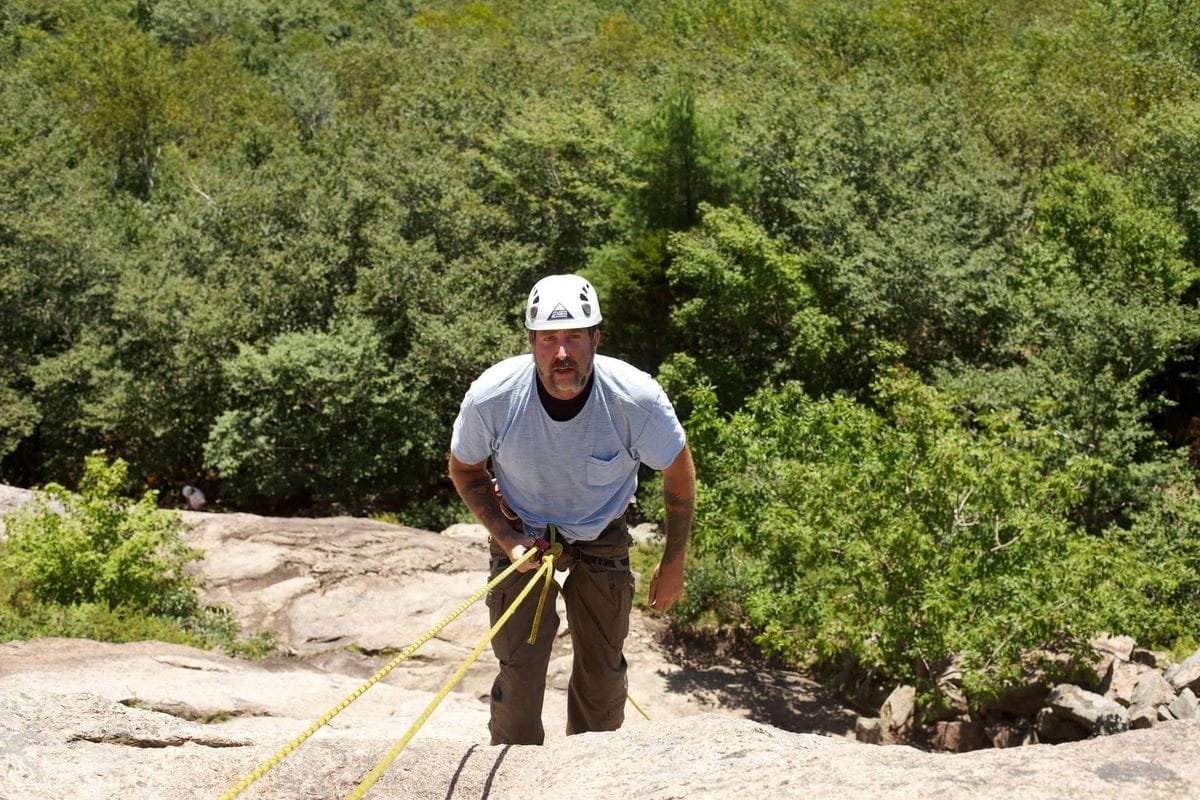 Nute on a rock face with a helmet and rope
